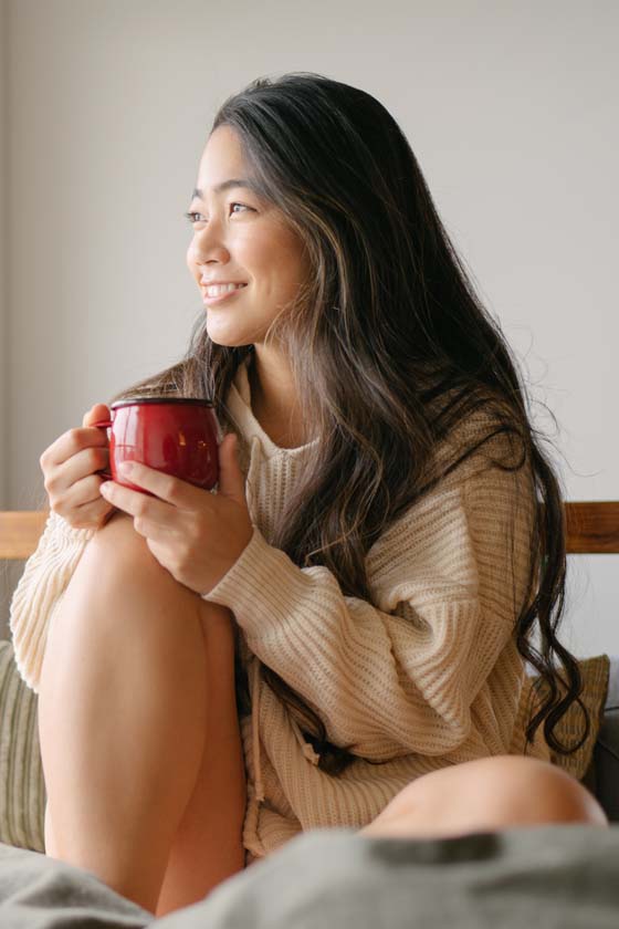 Woman sitting and smiling enjoying a cup of coffee
