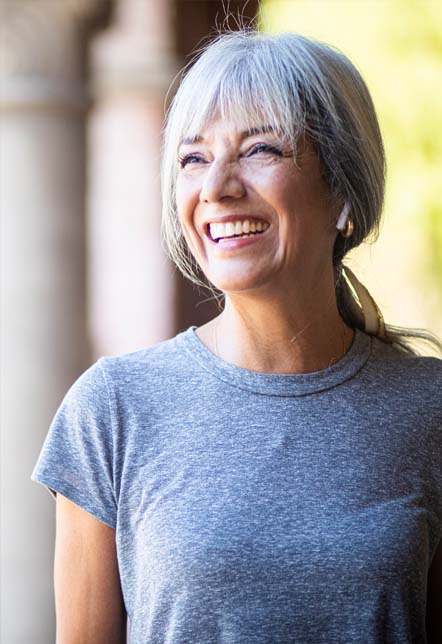 Older woman wearing a gray tee shirt and smiling